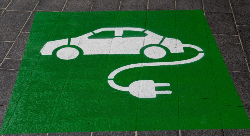 A car with an electric cord is painted on the ground to signify electric charging. 